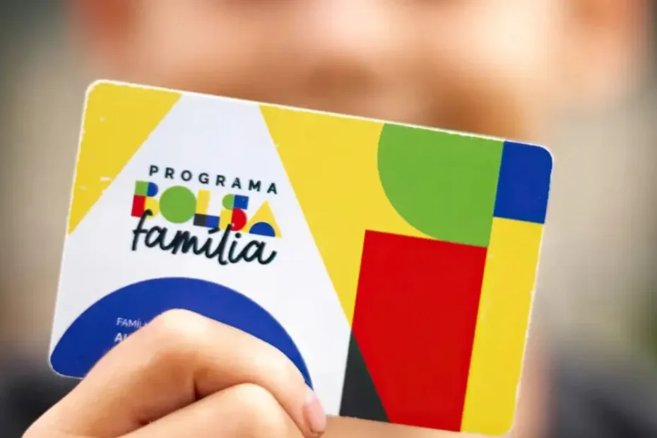 Mãe sorri com bebê no colo segurando cartão do Bolsa Família.