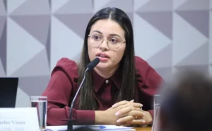 Mulher depõe à CPMI do INSS com semblante emocionado enquanto parlamentares a observam.