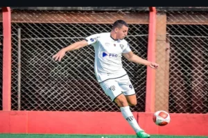 Jogador de futebol pensativo em campo ao pôr do sol