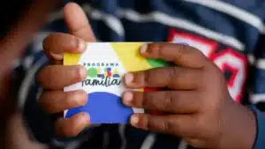 Mãe com filhos recebendo informações sobre o Bolsa Família em um centro comunitário.