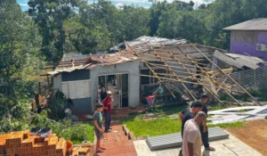 Ruas de Palmeira das Missões com casas danificadas após temporal, moradores observam estragos.