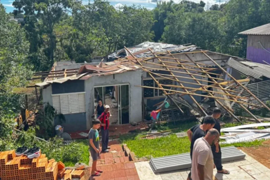 Ruas de Palmeira das Missões com casas danificadas após temporal, moradores observam estragos.