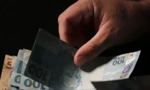 Idosa sorri ao verificar extrato bancário com pagamento do 13º salário do INSS.