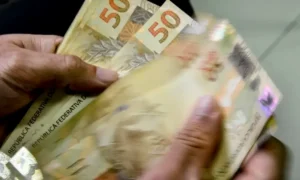 Trabalhador celebra recebimento de abono salarial no celular