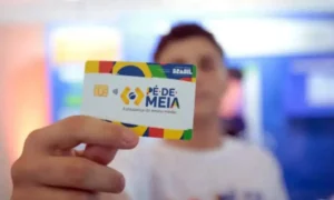 Jovem estudante verificando o pagamento do Pé-de-Meia no aplicativo CAIXA Tem do celular.