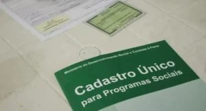 Mulher preocupada em frente ao balcão do CRAS com documentos na mão para atualizar o CadÚnico.