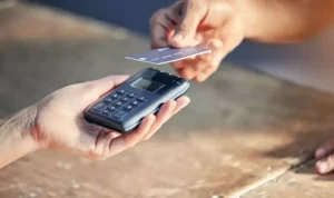 Pessoas em uma comunidade urbana usando smartphones para acessar aplicativos de bancos.