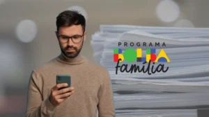 Mulher preocupada olha para celular com app do Bolsa Família indicando possível bloqueio de benefício