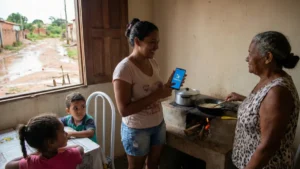 Trabalhador da Caixa entrega cartão do Bolsa Família para família.