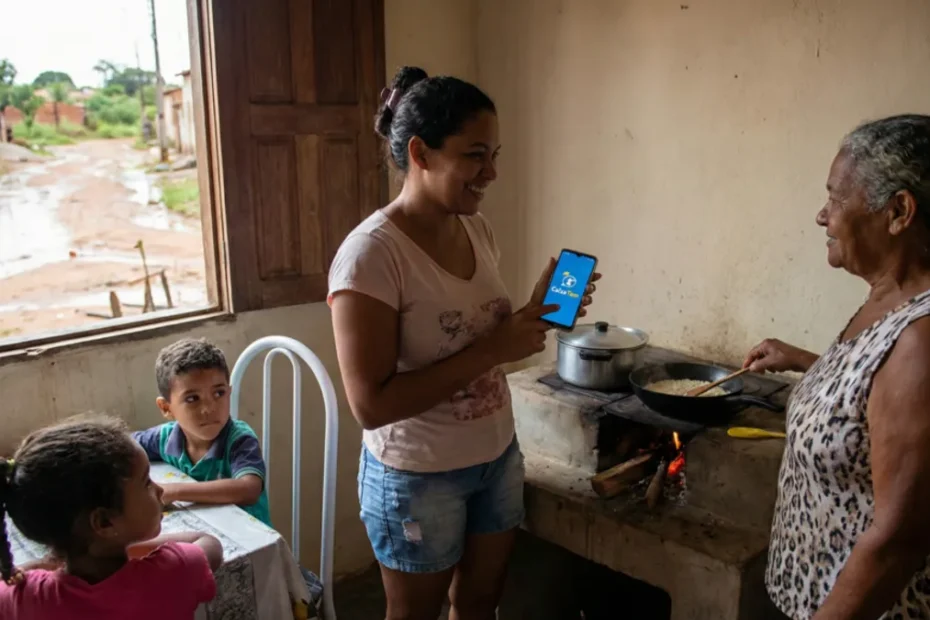 Trabalhador da Caixa entrega cartão do Bolsa Família para família.