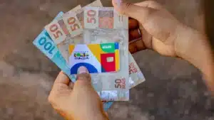 Família recebe cartão do Bolsa Família em agência lotérica.