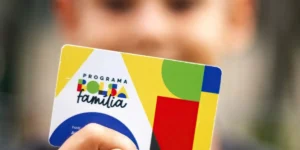Mulher brasileira verificando saldo do Bolsa Família no celular com expressão de alívio