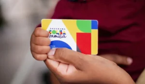 Mulher sorrindo ao conferir pagamento do Bolsa Família no celular