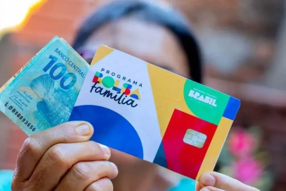 Mão segurando celular com o aplicativo Caixa Tem aberto, indicando recebimento de Bolsa Família e Pé-de-Meia