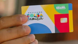 Funcionário do TCU analisando documentos relacionados a programas sociais.
