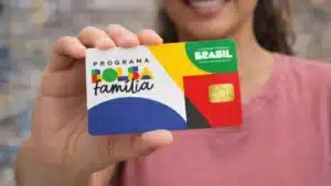 Mãe e filhos olhando celular com notificação do Bolsa Família