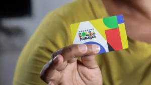 Mulher sorri ao verificar pagamento do Bolsa Família no celular.