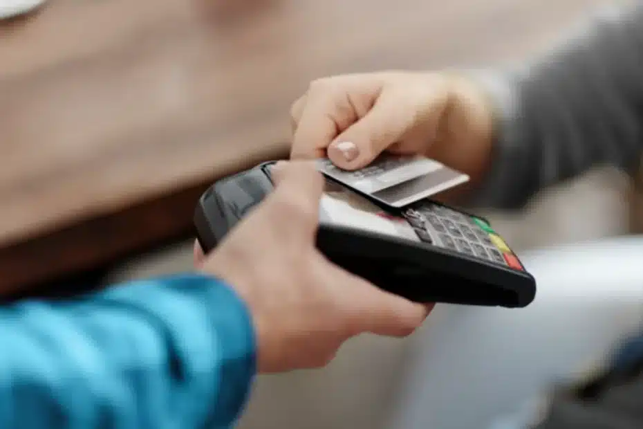 Mão segurando cartão de crédito em ambiente de compras