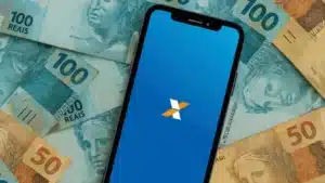 Homem consulta aplicativo da Caixa no celular em frente a uma agência