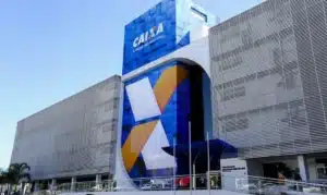 Fachada iluminada de uma agência da Caixa Econômica Federal com o logo em destaque.