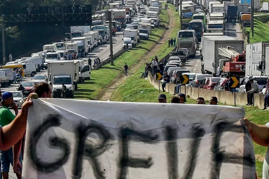 Caminhoneiro olha apreensivo para o preço alto do diesel em um posto de combustível.