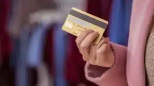 Mão segurando um cartão de crédito premium em um ambiente de luxo, representando benefícios de viagem.