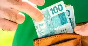 Mãos trocando dinheiro ou um cartão de benefício, com uma conta de luz ou botijão de gás ao fundo, simbolizando auxílios financeiros e sociais.