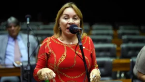 Tornozeleira eletrônica no tornozelo de uma pessoa em ambiente que sugere contexto de investigação política.