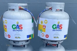 Mulher sorri ao receber botijão de gás através do programa Gás do Povo