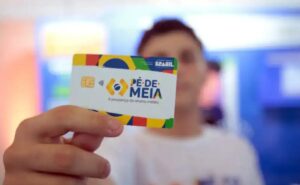 Jovem estudante sorrindo ao consultar o pagamento do Pé-de-Meia pelo celular