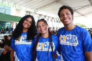 Estudante feliz olhando o celular com notificação de pagamento do Pé-de-Meia