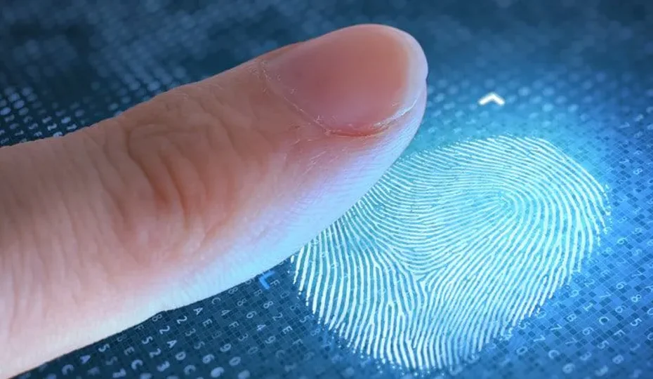 Mão de pessoa registrando biometria em leitor digital, com fundo desfocado de alguém consultando documentos ansiosamente