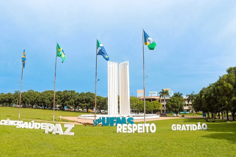 Estudante sorri enquanto usa laptop para se inscrever em auxílio estudantil da UFMS.
