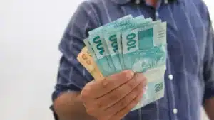 Trabalhador brasileiro com contracheque mostrando o novo salário mínimo de 2026.