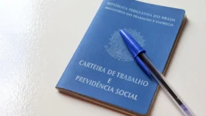 Trabalhador pensativo em frente a um computador, com documentos ao lado, representando a situação de pejotização.