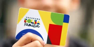 Mãos de beneficiário usando o aplicativo Caixa Tem para consultar o Bolsa Família.