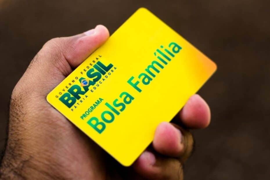 Mulher feliz recebendo cartão do Bolsa Família em agência da Caixa