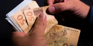 Tela do aplicativo Caixa Tem com notificação de pagamento de benefício, e família brasileira ao fundo.