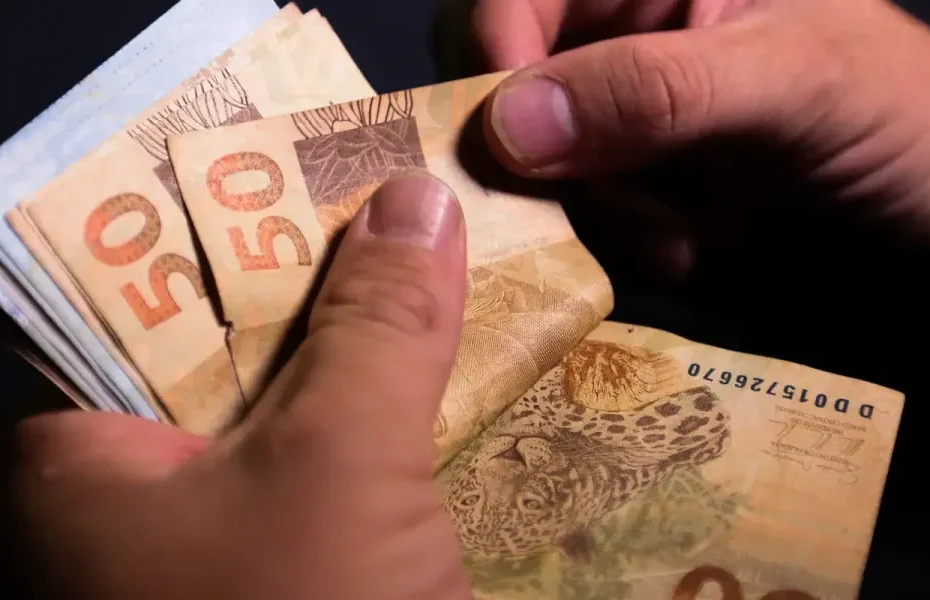 Tela do aplicativo Caixa Tem com notificação de pagamento de benefício, e família brasileira ao fundo.