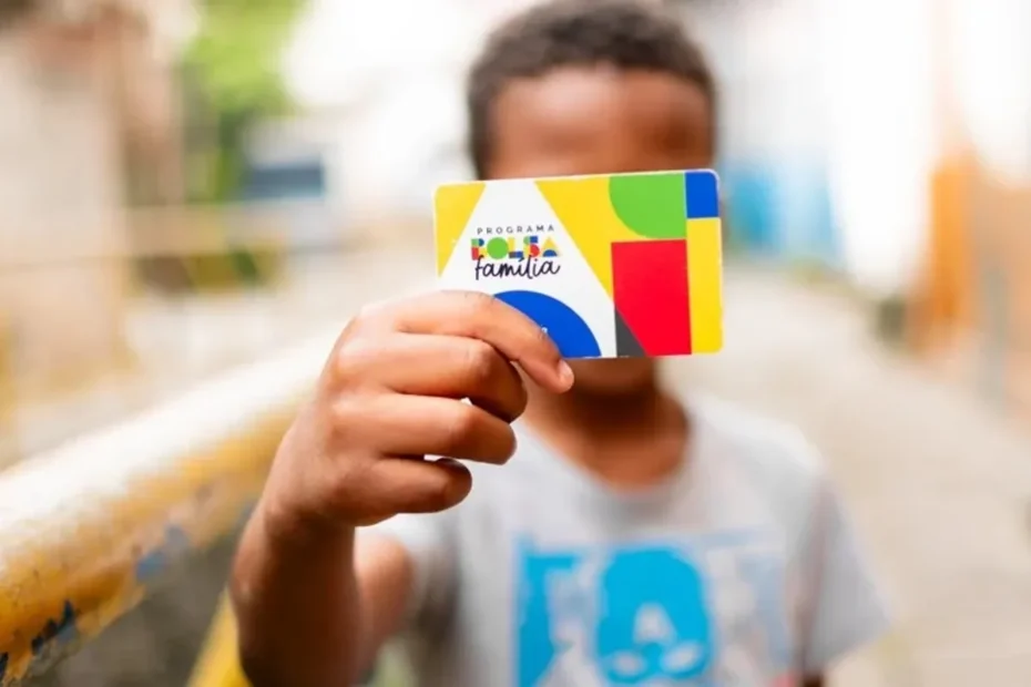 Mãe sorrindo com cartão de benefício em mãos ao lado de seu filho em Pernambuco ou Ceará.
