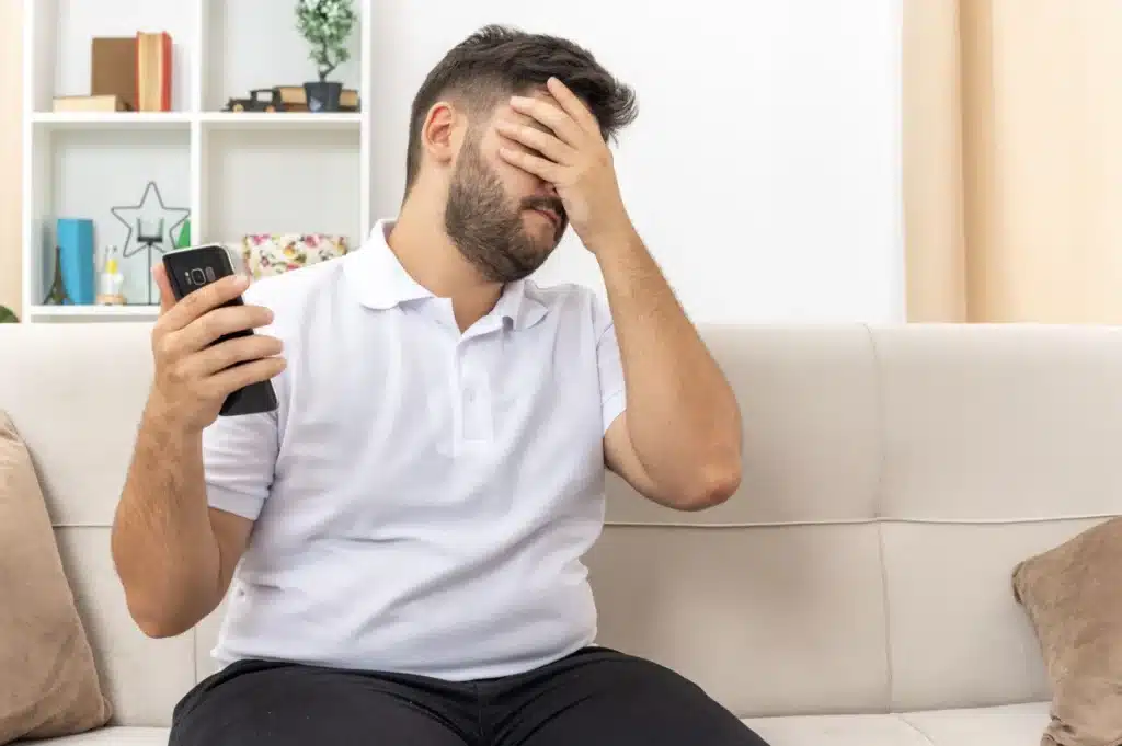 Pessoa checando aplicativo financeiro bloqueado no celular, simbolizando restrição a plataformas como Polymarket e Kalshi.
