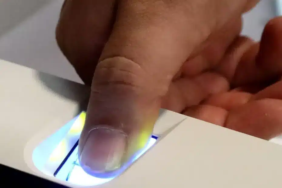 Mão de pessoa registrando biometria em scanner para acesso a benefício social