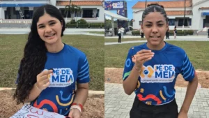 Jovem estudante sorrindo, com cadernos e celular, simbolizando investimento na educação com o Pé-de-Meia.