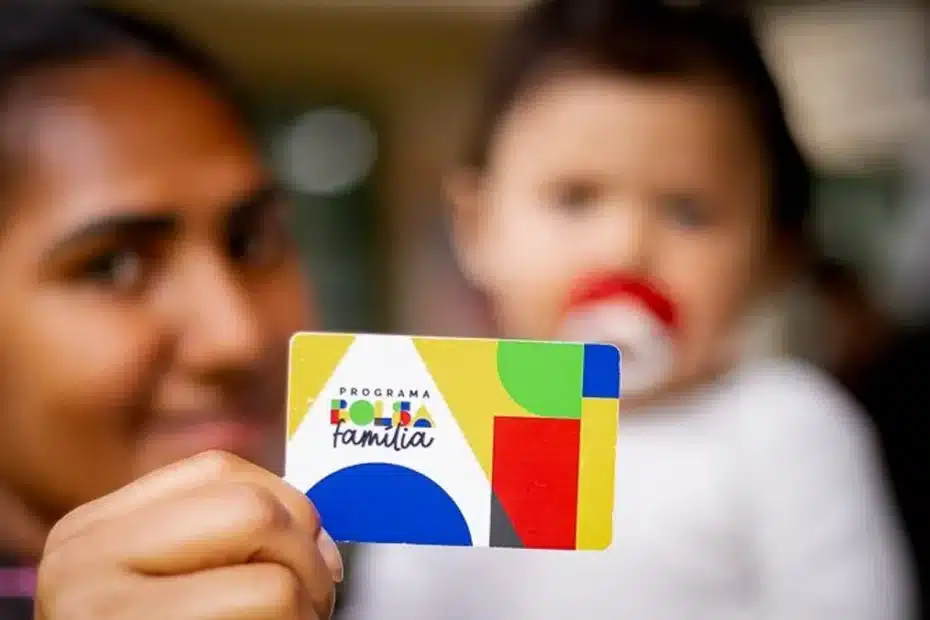 Beneficiária do Bolsa Família com cartão em mãos.