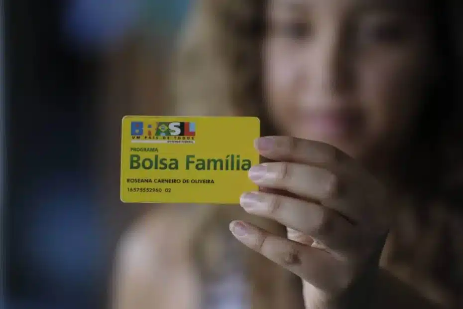 Mulher recebendo cartão do Bolsa Família
