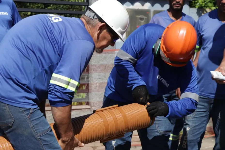 Trabalhadores instalam tubulações de esgoto em canteiro de obras no bairro Paranaguamirim, em Joinville, parte do projeto de expansão da rede de saneamento.