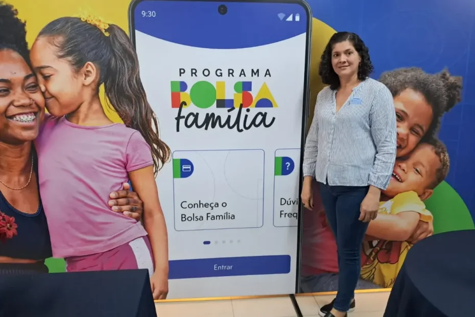 Mulher sorri enquanto consulta informações do Bolsa Família em seu smartphone através do novo aplicativo oficial.