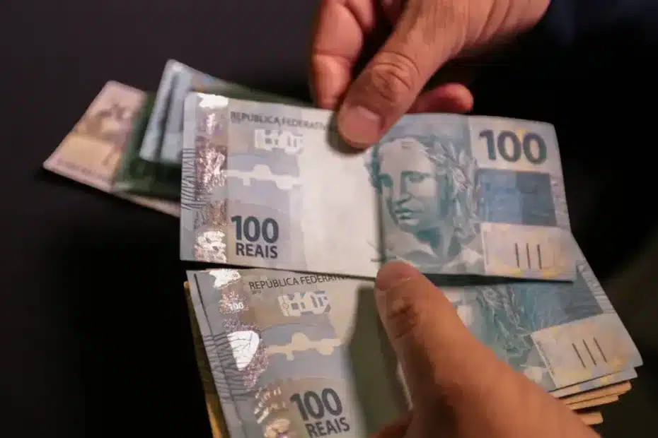 Mão segurando celular com extrato bancário mostrando aumento de salário no RS