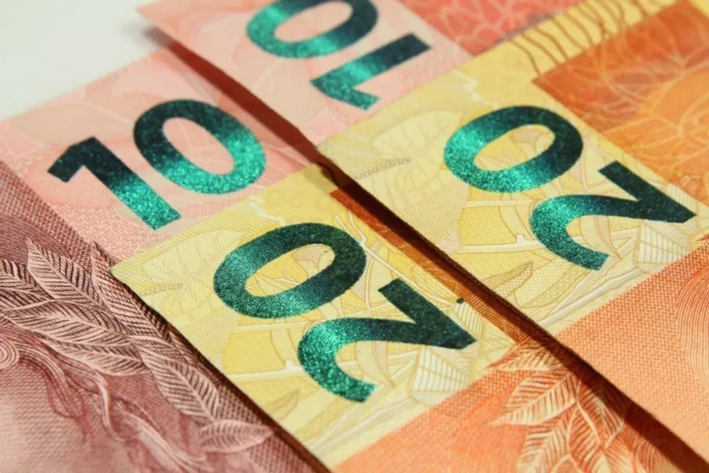 Mãos segurando dinheiro e apontando para datas de salário mínimo futuro