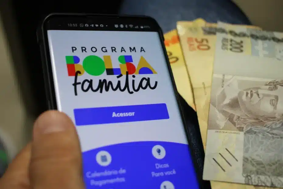 Mãe de família consulta informações do Bolsa Família no celular com expressão de alívio.